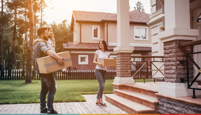 a family standing in front of a house holding boxes