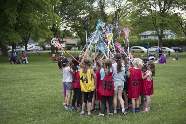 Brian and lacrosse team huddle for a cheer on the field